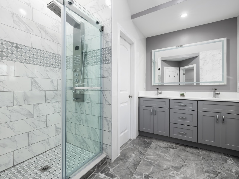 waterproofing shower floor in a modern tiled bathroom with glass shower enclosure