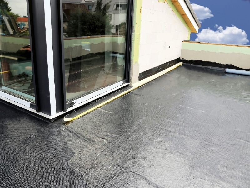 Completed waterproofing balcony floor with seamless membrane finish and clean edges near glass sliding doors