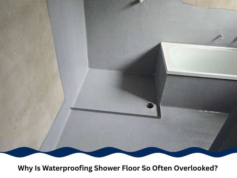 Waterproofing shower floor with grey sealant coating around drain and bathtub area.